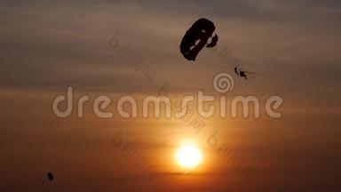 日落时在热带海滩进行降落伞活动。 平静的海水和。 带降落伞的海滩娱乐活动。 拖着一个